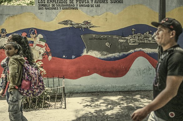 People walk past a mural of Venezuela’s warship and warplanes on a street in Caracas in September.