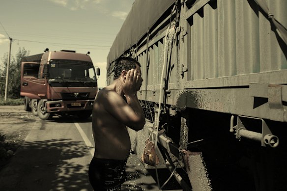 A driver showers with a makeshift contraption rigged to his coal truck during a days-long jam on the Beijing-Tibet Expressway in 2010. 