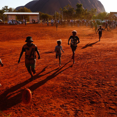 Mutitjulu children playing footy during the closing ceremony in the shadow of Uluru.