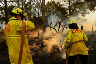 Firefighters hose down  the terrain after extinguishing flames near Bargo.