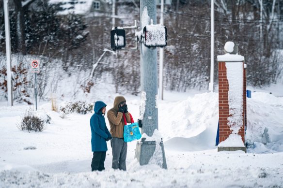 Pedestrians wait to cross the street during a winter storm in Iowa ahead of the caucuses.