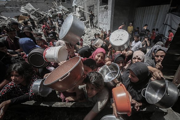 Displaced Palestinians collect cooked food from a community kitchen in Jabalia, northern Gaza, on Monday.