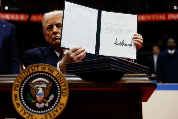 President Donald Trump holds up one of the executive orders he signed at the public rally in Washington’s Capitol One Arena.