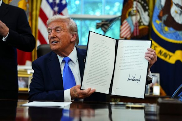 Donald Trump displays the executive order authorising the new visa fee.