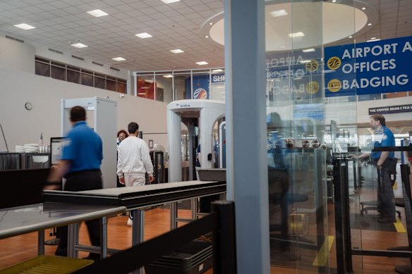 A migrant (in white) passes through security before boarding a flight in Shreveport, Louisiana, US. The Trump administration has been moving detained migrants to former prisons in Louisiana.