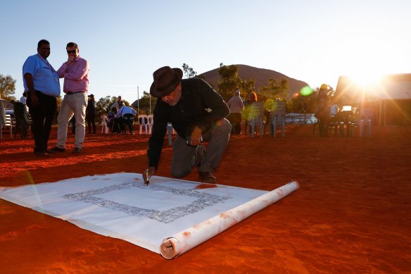 Indigenous person  Noel Pearson signs the canvas utilized  for the Uluru Statement from the Heart's artwork successful  2017.
