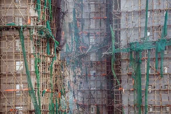 Styrofoam boarded windows at the towers, seen behind scaffolding and green netting.