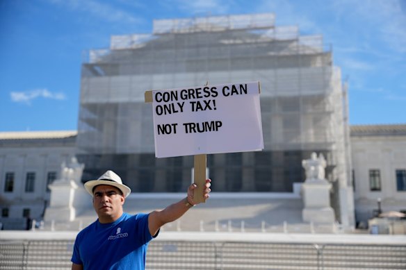 A demonstrator outside the US Supreme Court on Wednesday (Thursday AEDT), where the tariff case was being heard.