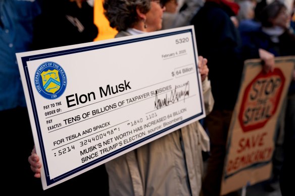 A demonstrator holds a fake cheque during a protest against Elon Musk outside the US Treasury building in Washington this week.