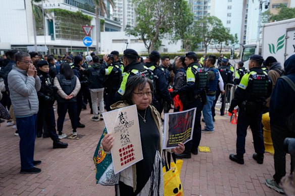 A woman holds posters with slogans outside the West Kowloon Court following a sentencing hearing for former media mogul Jimmy Lai in Hong Kong.