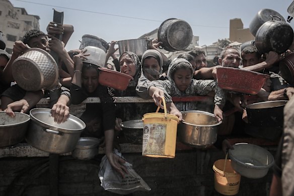 Palestinians gather to receive food from a charity distribution point in the city of Gaza.
