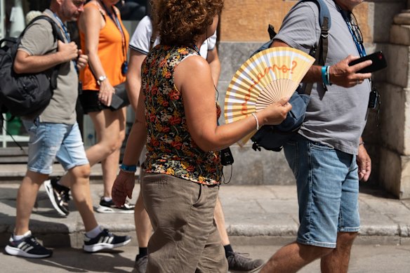 A tourist uses a hand fan during a heatwave in Palermo.