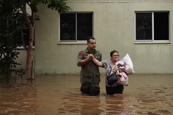 A worker  helps a pistillate   evacuate from a neighbourhood successful  Canoas flooded by dense  rain.