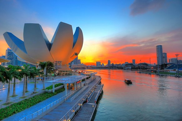 Iconic lotus flower-shaped ArtScience Museum on the Singapore River at sunset.