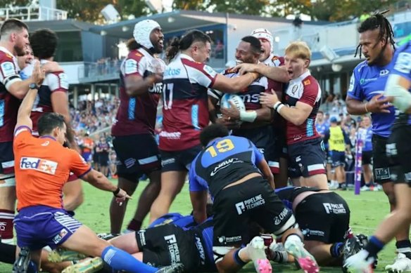 Reds players swamp Filipo Daugunu (with ball) after his late try to beat the Force.