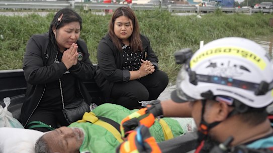 Krongkarn Jantarasavad (left) praying over her father, who missed dialysis treatment because floods had trapped him inside the family home.