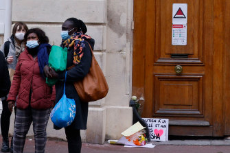 Les habitants se tiennent à côté de fleurs déposées à l'entrée du lycée Cognacq-Jay à Argenteuil en hommage à la jeune fille de 14 ans dont le corps battu a été retrouvé dans la Seine.