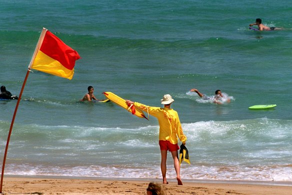 A surf lifesaver warns swimmers to move back inside the flags. 