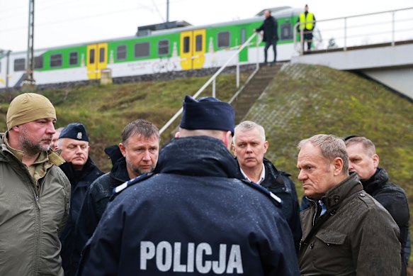 Prime Minister Donald Tusk, second right, visits the site of the rail line sabotage attack.