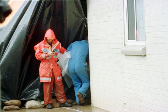 A police officer carrying a body bag enters the excavation site at the rear of a Housing Trust home at Salisbury North as part of the Snowtown murders investigation in 1999.