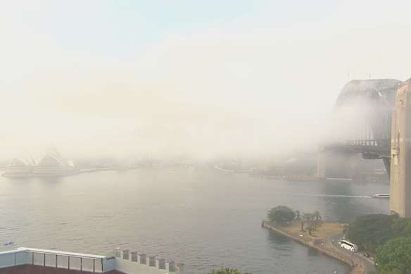 The Sydney Opera House and Harbour Bridge in a view of the city obscured by fog.