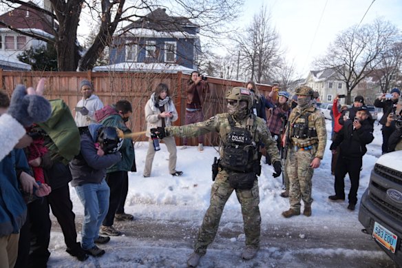 A law enforcement agent sprays a line of protesters with chemical spray at the scene of the shooting in Minneapolis.