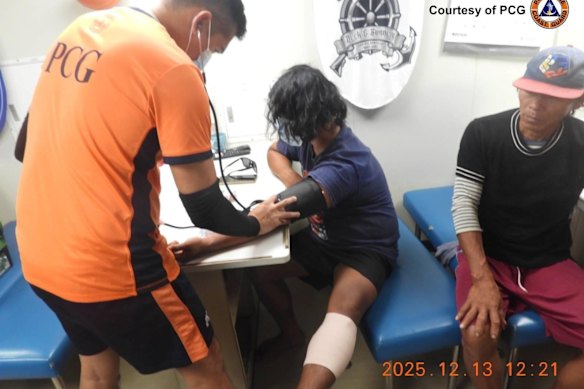 In this photo provided by the Philippine Coast Guard, Philippine Coast Guard personnel treat wounded fishermen inside their vessel at the disputed South China Sea.