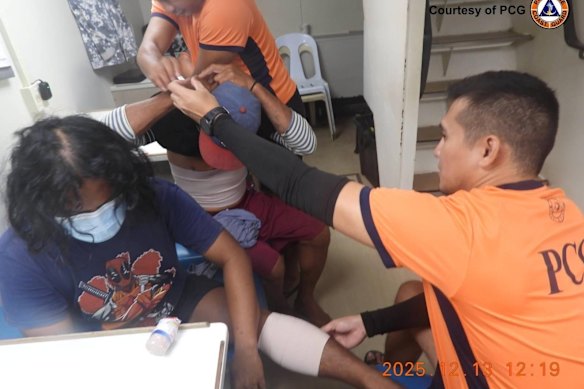 In this photo provided by the Philippine Coast Guard, personnel treat wounded fishermen inside their vessel at the disputed South China Sea on Saturday.