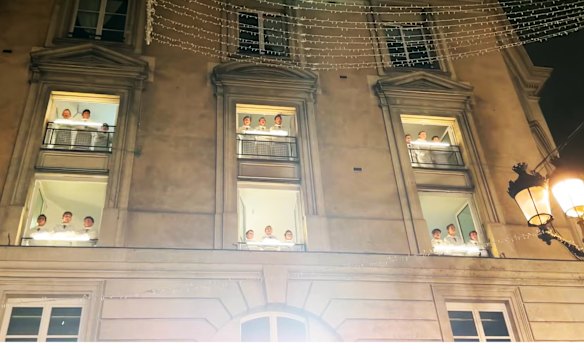 Choristers sing from windows as the crowd enjoys the Carol of the Bells flash mob in Paris.