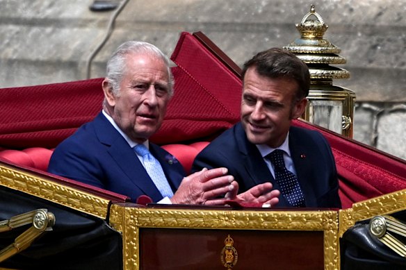 King Charles and French President Emmanuel Macron ride a horse-drawn carriage towards Windsor Castle.