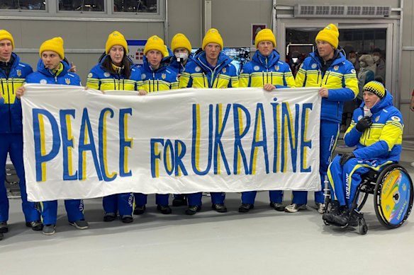 Members of Ukraine’s Paralympic team hold us a sign for peace in 2022.
