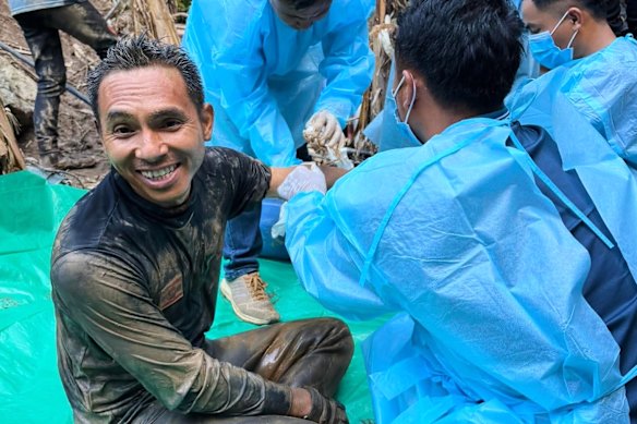 A rescuer smiles after five people trapped in the cave in Laos were located.