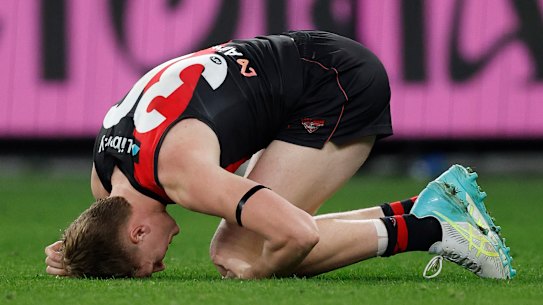 Essendon’s Angus Clarke reels after getting a knock.
