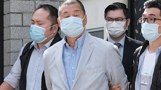 Jimmy Lai, second left, is led away from his residence by law enforcement officials in Hong Kong on Monday. 