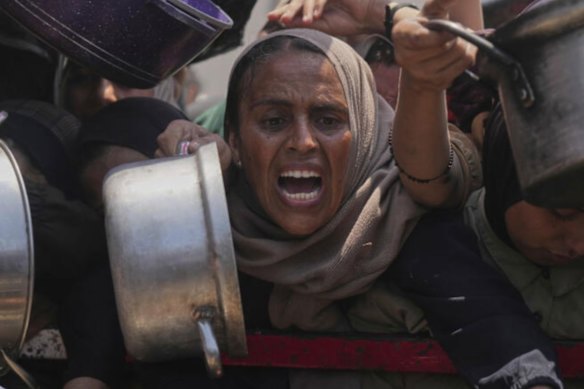 Palestinians struggle to get donated food at a community kitchen, in Gaza City, northern Gaza Strip.