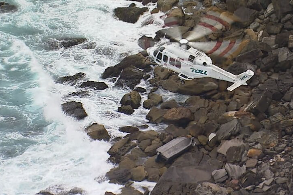 A rescue helicopter circles over the boat wedged in rocks at Palm Beach.