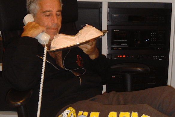 Jeffrey Epstein contemplates a cake in the shape of women’s breasts in a newly released photograph.