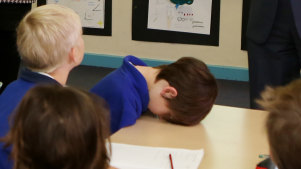 A student takes a rest when then-Prime Minister Tony Abbott makes a school visit.