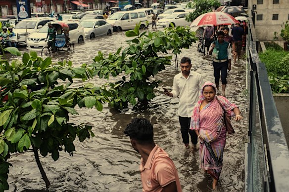 People in Dhaka wade through floodwaters in September 2025.

