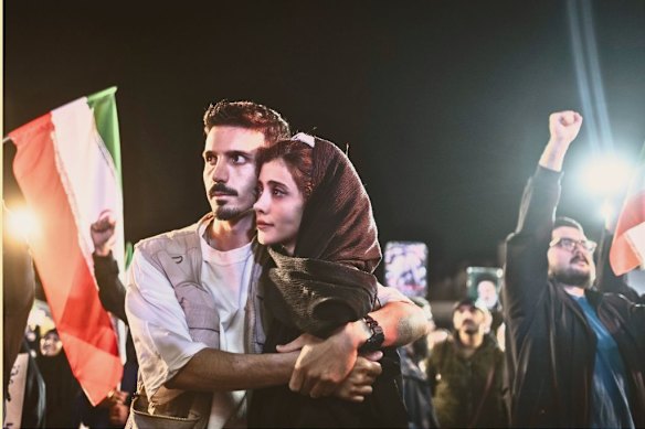 In Tehran, a couple embraces as other pro-government Iranians shout slogans during the April 8 funeral for a senior figure in Iran’s Revolutionary Guard Corps, killed in US-Israeli air strikes.