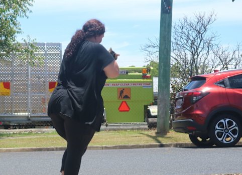 A young woman carries her cat from the remains of her burnt-out home after discovering him alive hours after the fire.