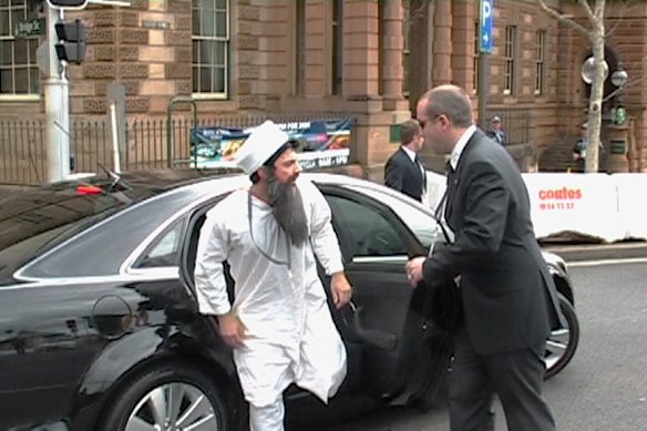 Chas Licciardello dressed as Osama bin Laden getting out of the motorcade car, with the door held by Julian Morrow.