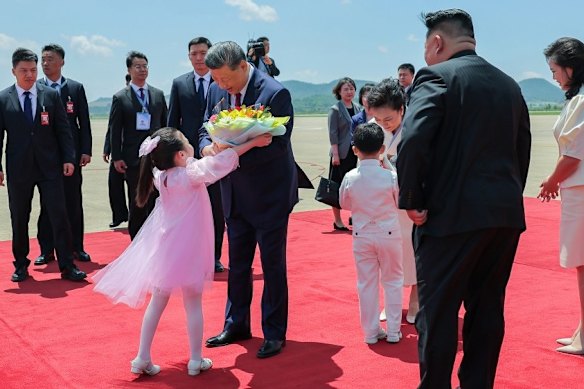 North Korean children present Xi and his wife, Peng Liyuan, with bouquets of flowers at the welcome ceremony, as Kim Jong-un and his wife, Ryu Sol-ju look on.