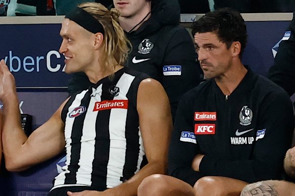 Darcy Moore (left) and Scott Pendlebury (centre) watch Friday night’s match from the bench.