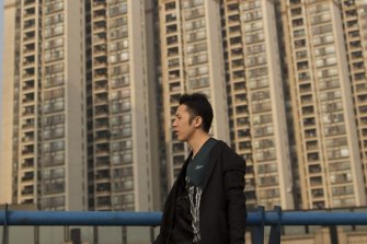 A man walks past residential buildings in the Pazhou district of Guangzhou, Guangdong Province, China.