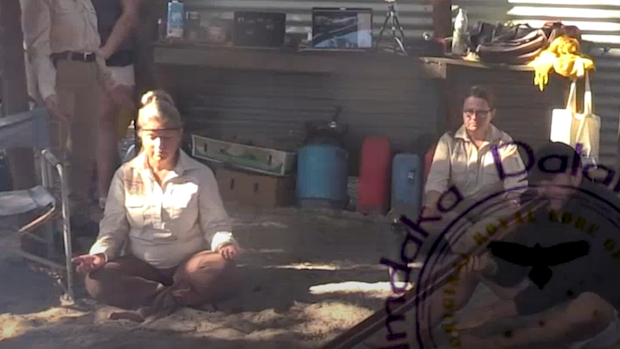 A screenshot from a since-deleted video posted on NDA’s website shows Helen Delaney (left) dressed in the organisation’s “sheriff” uniform, performing a cultural event at the camp. Many camp members were not Indigenous.