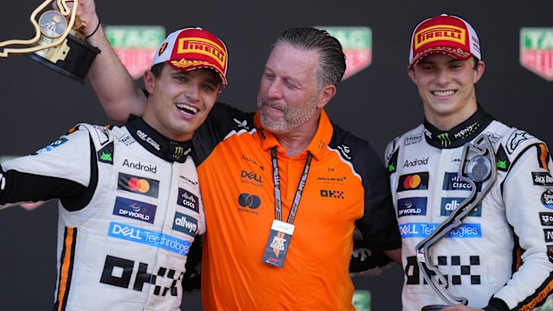 McLaren driver Lando Norris celebrates on the podium with Zak Brown, McLaren chief, and McLaren driver Oscar Piastri.