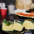 Khaman dhokla, in the foreground, is a steamed cake sprinkled with mustard seeds and curry leaves.