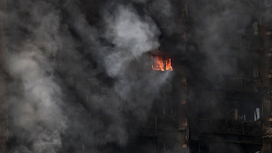 A fire still burns and smoke rises from the building after dawn on Wednesday.