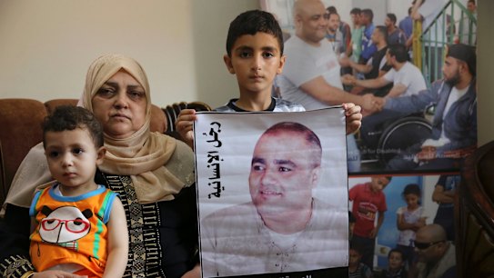 Amal al-Halabi, 57, holds her grandson Fares while her grandson Amro, 7, holds a poster demanding freedom for his father Mohammed al-Halabi, Gaza director of  World Vision.